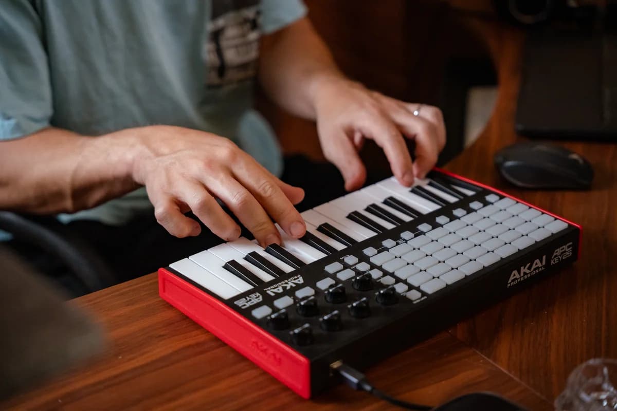 Hands playing a MIDI keyboard on the studio desk.