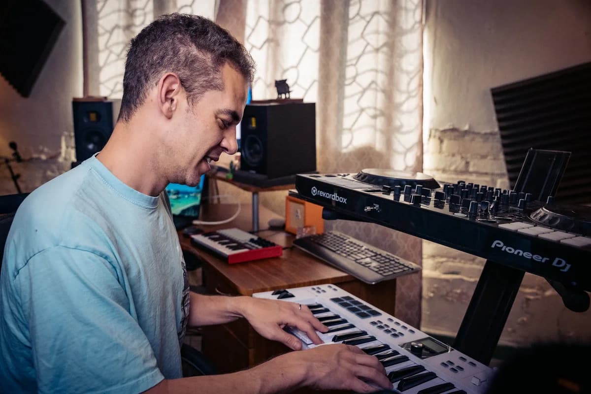 Playing a synthesiser beside the studio's mixing desk.